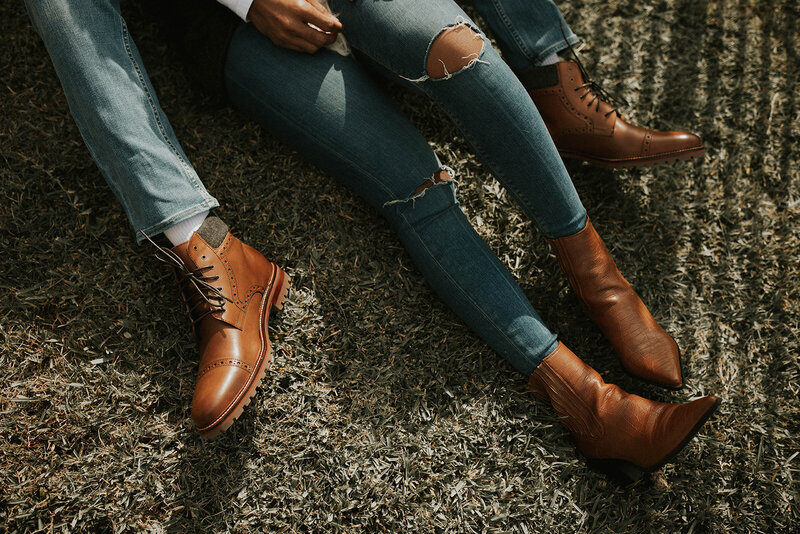 Close-up of the couple's legs and brown boots, sitting on grass.