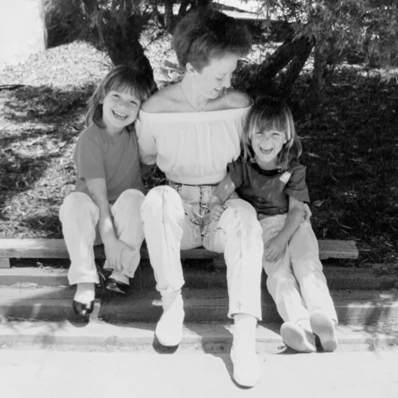 Nostalgic image of artist with her two young daughters seated and smiling
