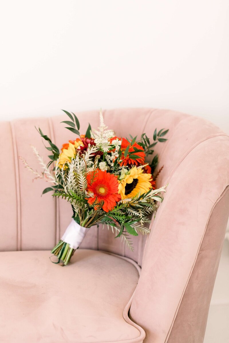 Bridal bouquet sitting on pink velvet chair, taken by minneapolis photographers