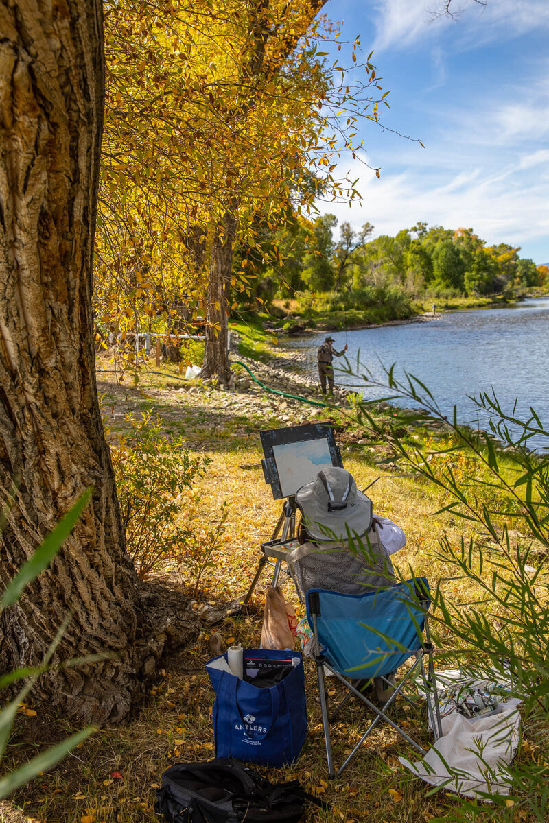 Woman painting fisherman by the river