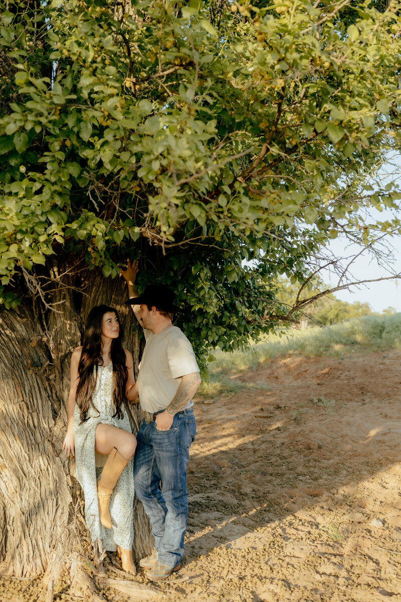 couple leaned up against a tree looking at each other