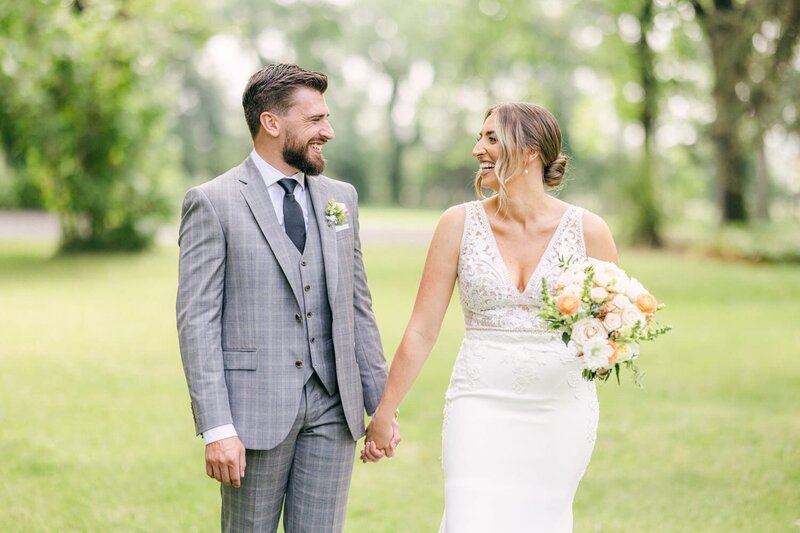 This image captures a bride and groom sharing a heartfelt laugh together at the Norland Estate in Lethbridge. Their laughter and the elegant setting of the estate reflect the happiness and love that define their special day.