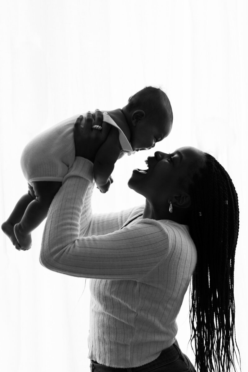 Black and white photo of a Mum playfully holding her son.