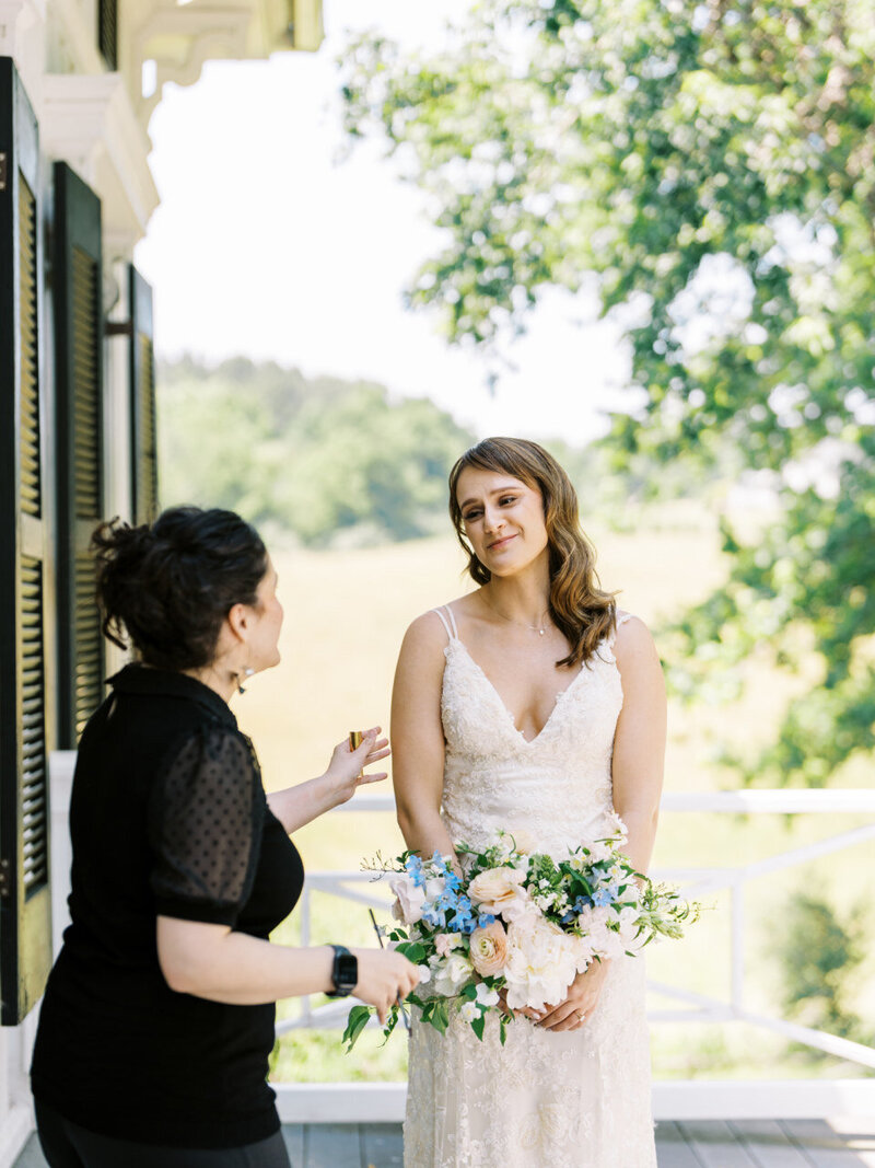 A girl in a black top talks to a bride holding a bouquet
