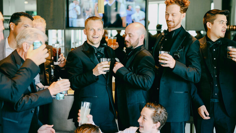 Groom celebrating with groomsmen in bar with drinks at Promontory Club Wedding Park City Utah by Cali Warner Media