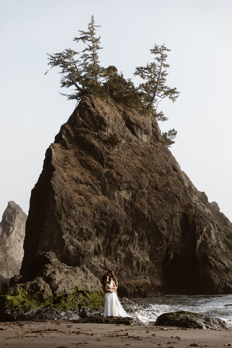 bride and groom embracing by rock