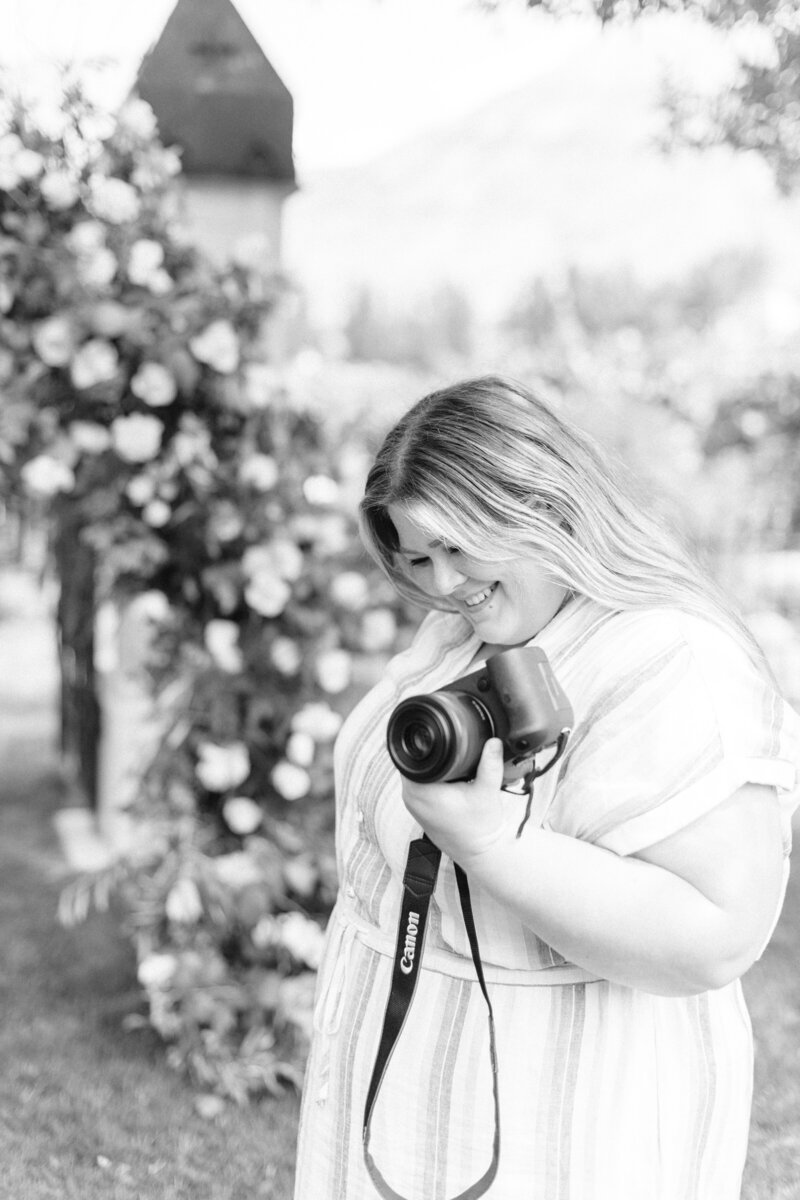black and white picture of Shalae holding camera and looking down while smiling