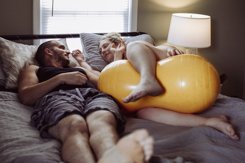 Soon-to-be Mom and Dad relax in bed in a quiet moment during labor, looking into eachother's eyes: birth photography in Tifton, Georgia