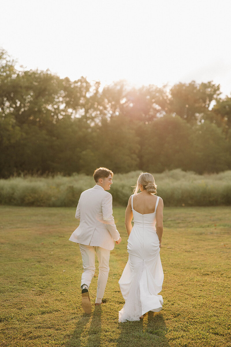 A couple running through a field wedding venue The Era
