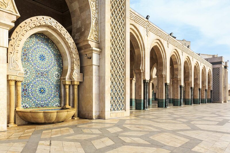 Ornate mosaic fountain and arches at Hassan II Mosque in Casablanca, Morocco, showcasing Islamic architecture.
