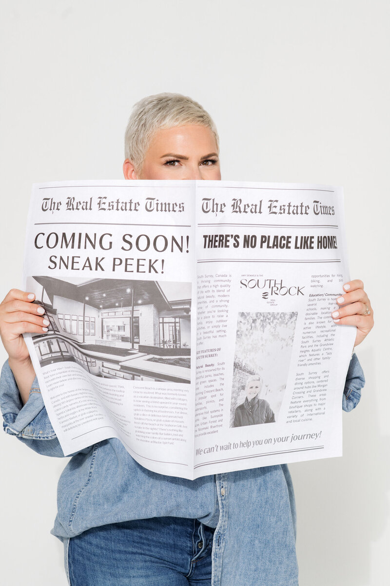 Amy Dewaele  peeking over a newspaper that says "Coming soon!"