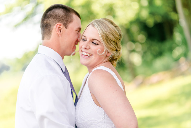Bride laughs while groom whisters in her ear