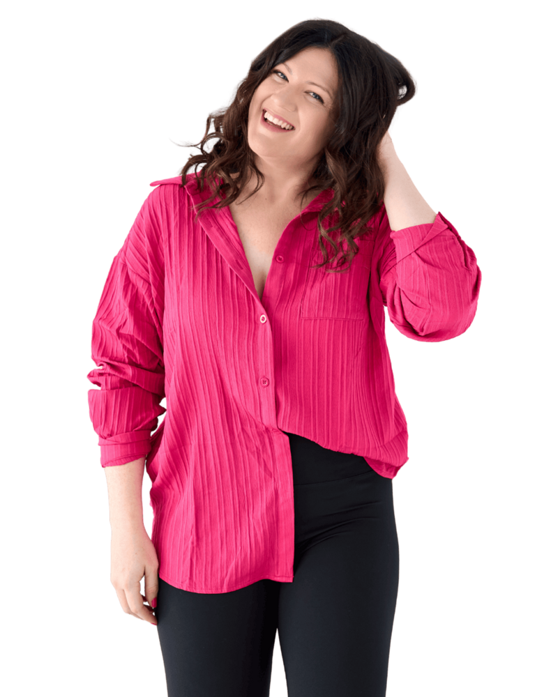 Emily wearing a pink button shirt, primping her hair and smiling at the camera.