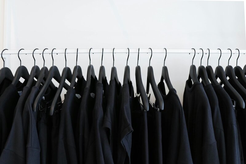 Black and white photo of clothing on hangers hanging on a rack