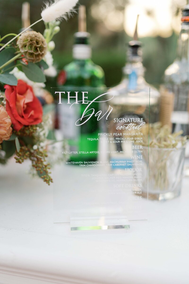 Clear acrylic bar menu at wedding cocktail hour.