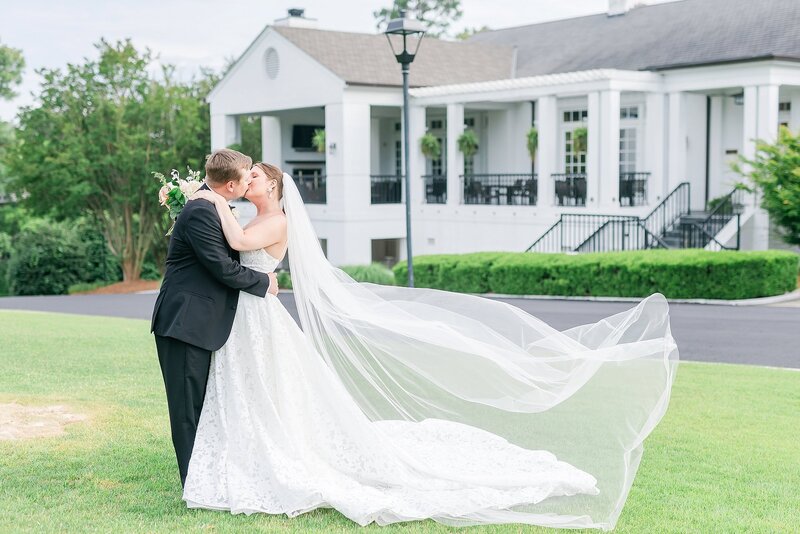 Bride and groom share a kiss with veil flying in the wind  at Country Club of Columbus | Columbus, GA Wedding Photographer Amanda Horne