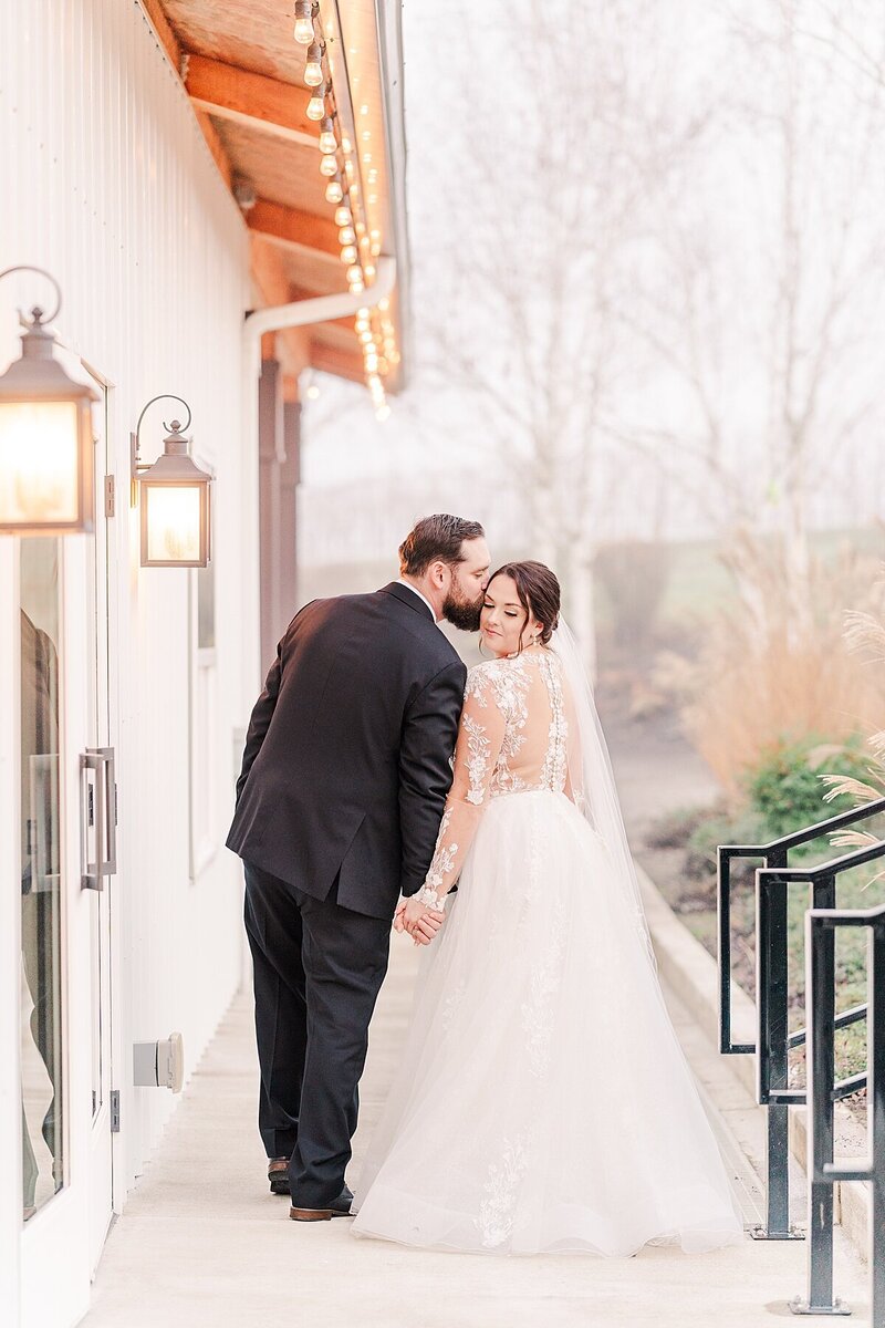 bride and groom standing together along reception hall at Aurora Vineyard at foggy wintery wedding