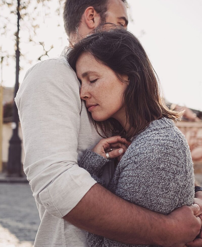 A couple embrace as the man wraps his arms around his wife. Idit Sharoni is a marriage counselor in Florida that offers support for infidelity recovery and other services. Contact our team to meet with a Florida therapist today!