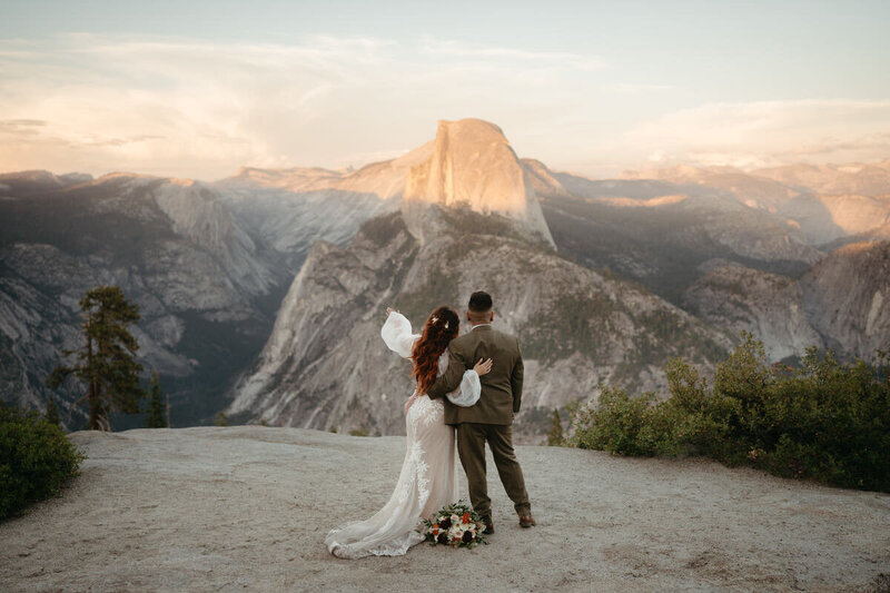 Bride and groom gaze in wonder at Half Dome during the sunset of their Glacier Point Wedding