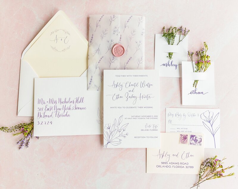 floral invitations with purple text and vellum wrap