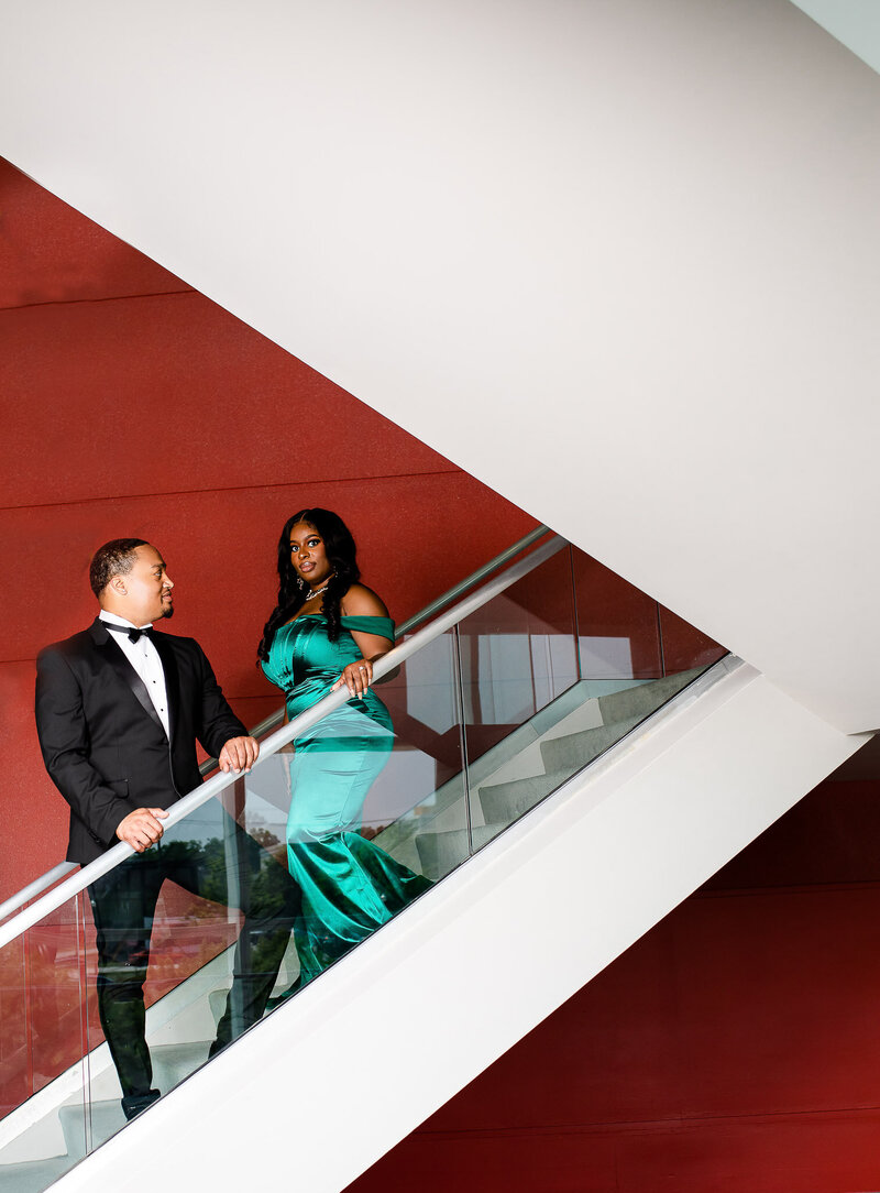 Engagement session black couple Columbia sc, in koger center in front of red wall wearing formal attire