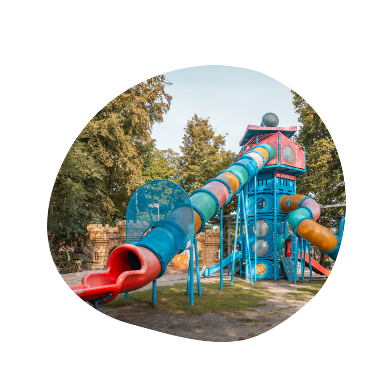 Glijbaan in speelpark Sprookjeshof, omringd door groen en speeltoestellen, met een vrolijke en kindvriendelijke uitstraling. 