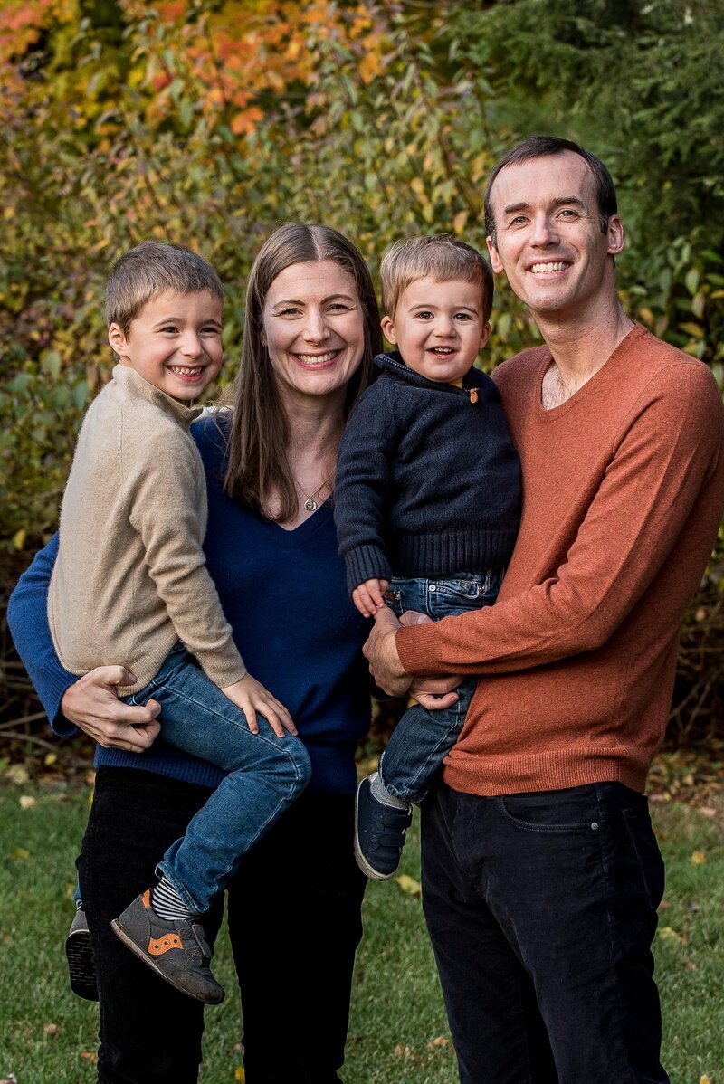 A family of four stand together smiling at the camera