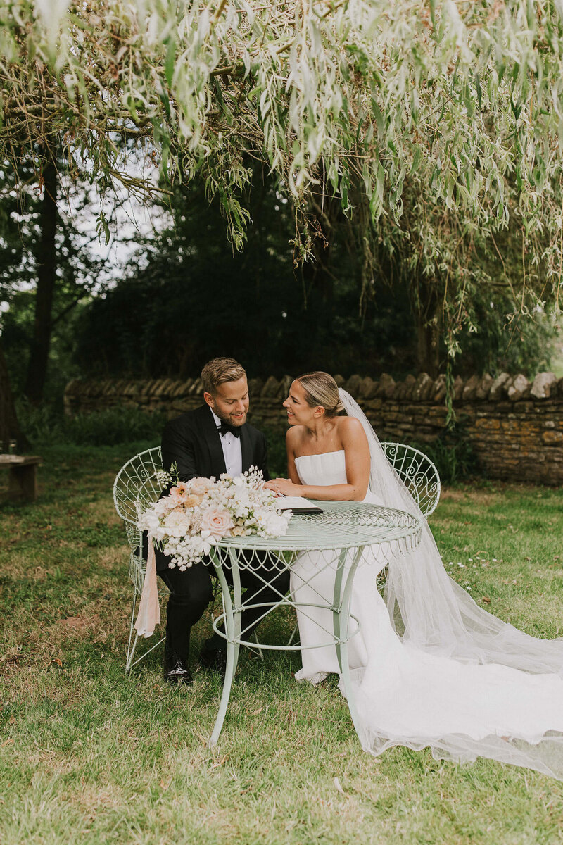 Bride and groom signing the register at Dewsall Court in the gardens