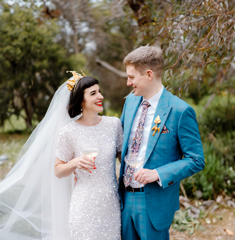 A bride and groom in and outside setting looking and smiling at each other