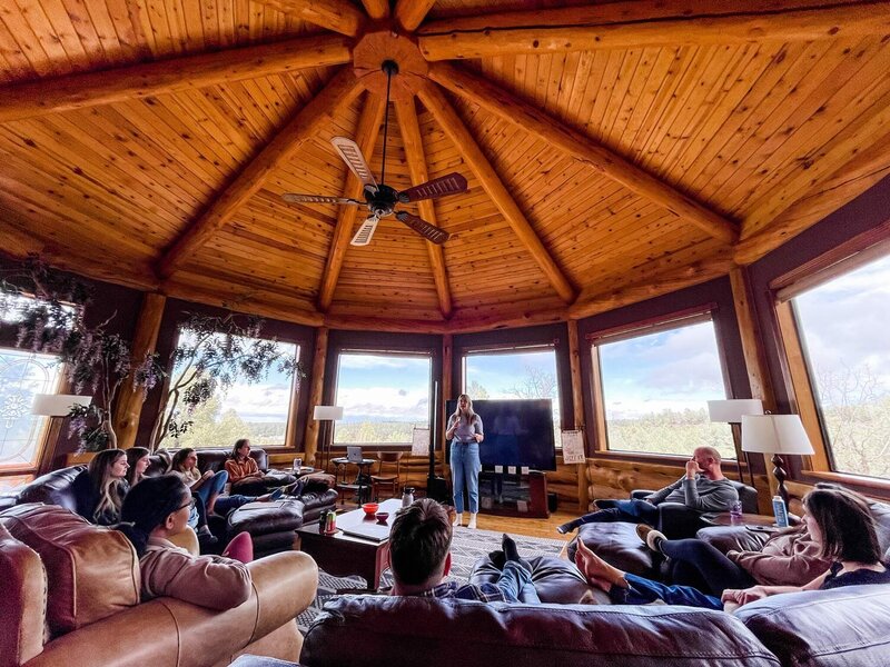 A group of women sit around a dining table smiling. 