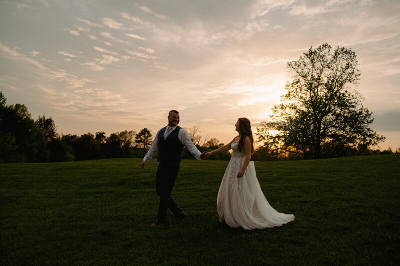 A bride and groom pose for their portrait at sunset.