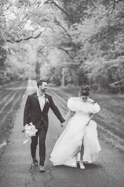 Black and white image of knoxville bride and groom holding hands walking down maple grove estate driveway