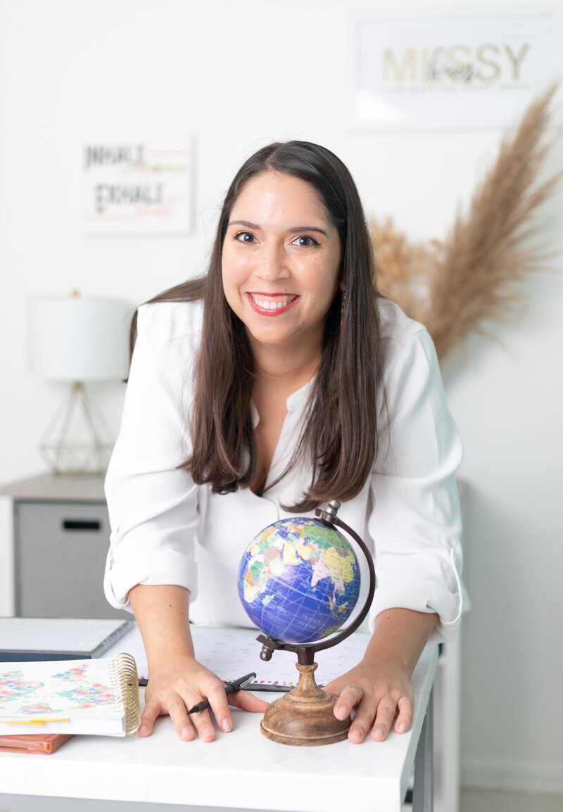 Woman leans on table with globe on it
