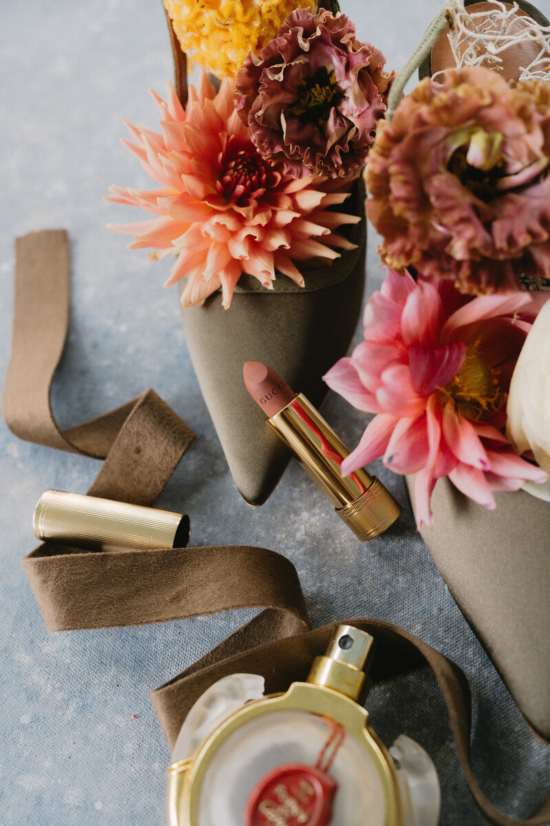 Wedding flatlay featuring blush florals, high heels, and Gucci lipstick from a Cove Mill Design Co. wedding at the Inn at Hastings Park in Lexington, MA.