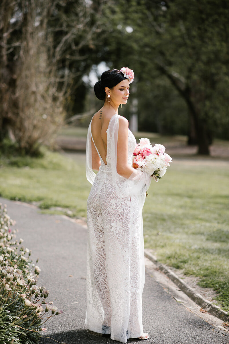 Bride with low back wedding dress and pink floral headpiece and bouquet