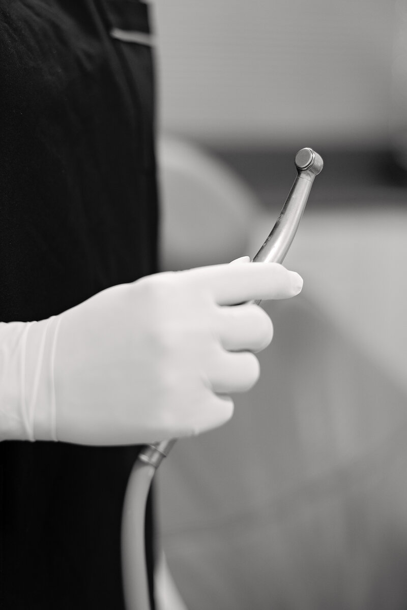gloved hand holding dental cleaning tools