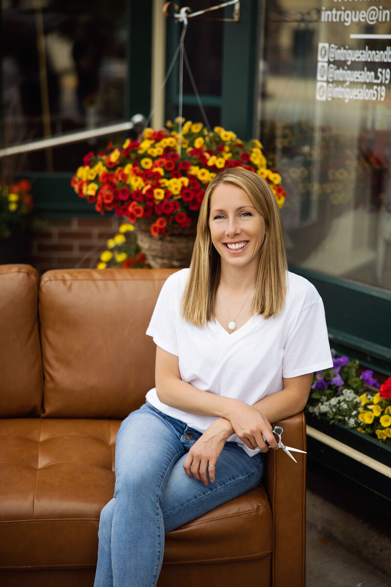 Tonna Irick, professional hair stylist at Intrigue Salon, holding styling tools and standing in front of a mirror in the salon