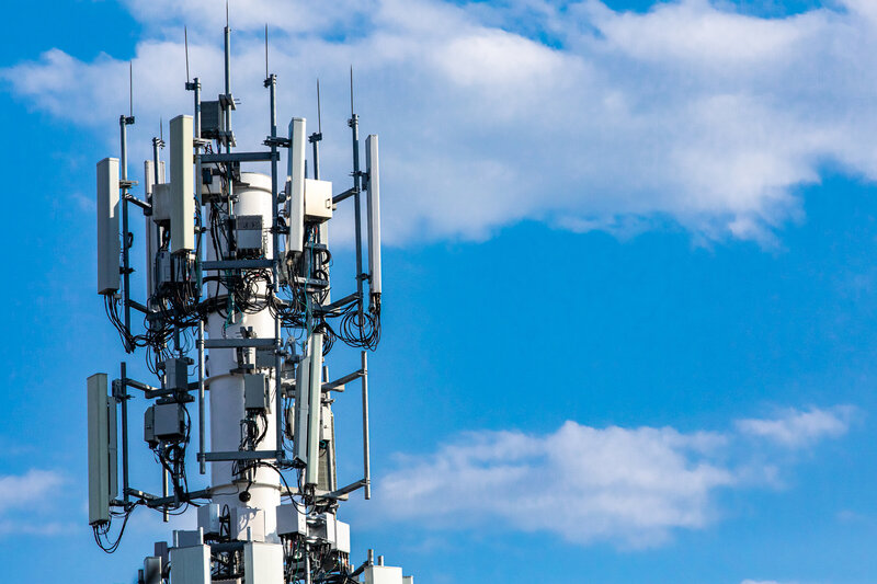 Cellphone tower with a blue sky and clouds in the background 