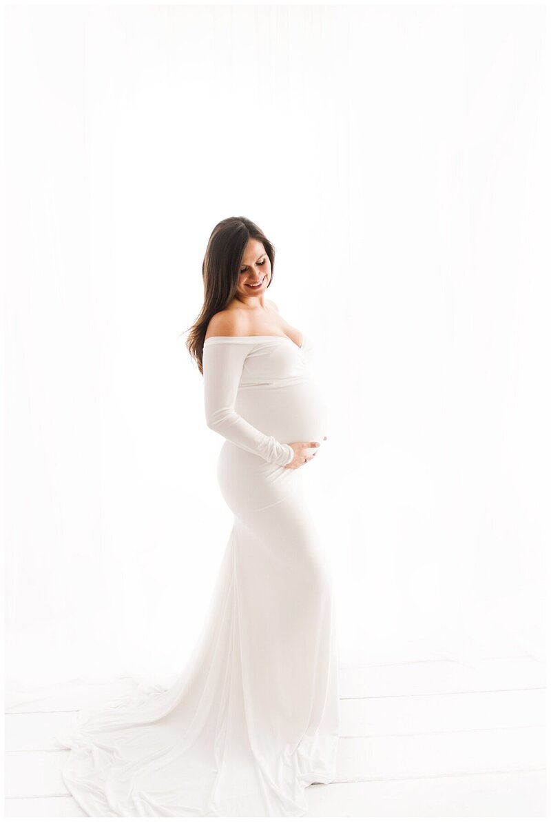 pregnant mom in white dress posing for maternity photographer in boston​