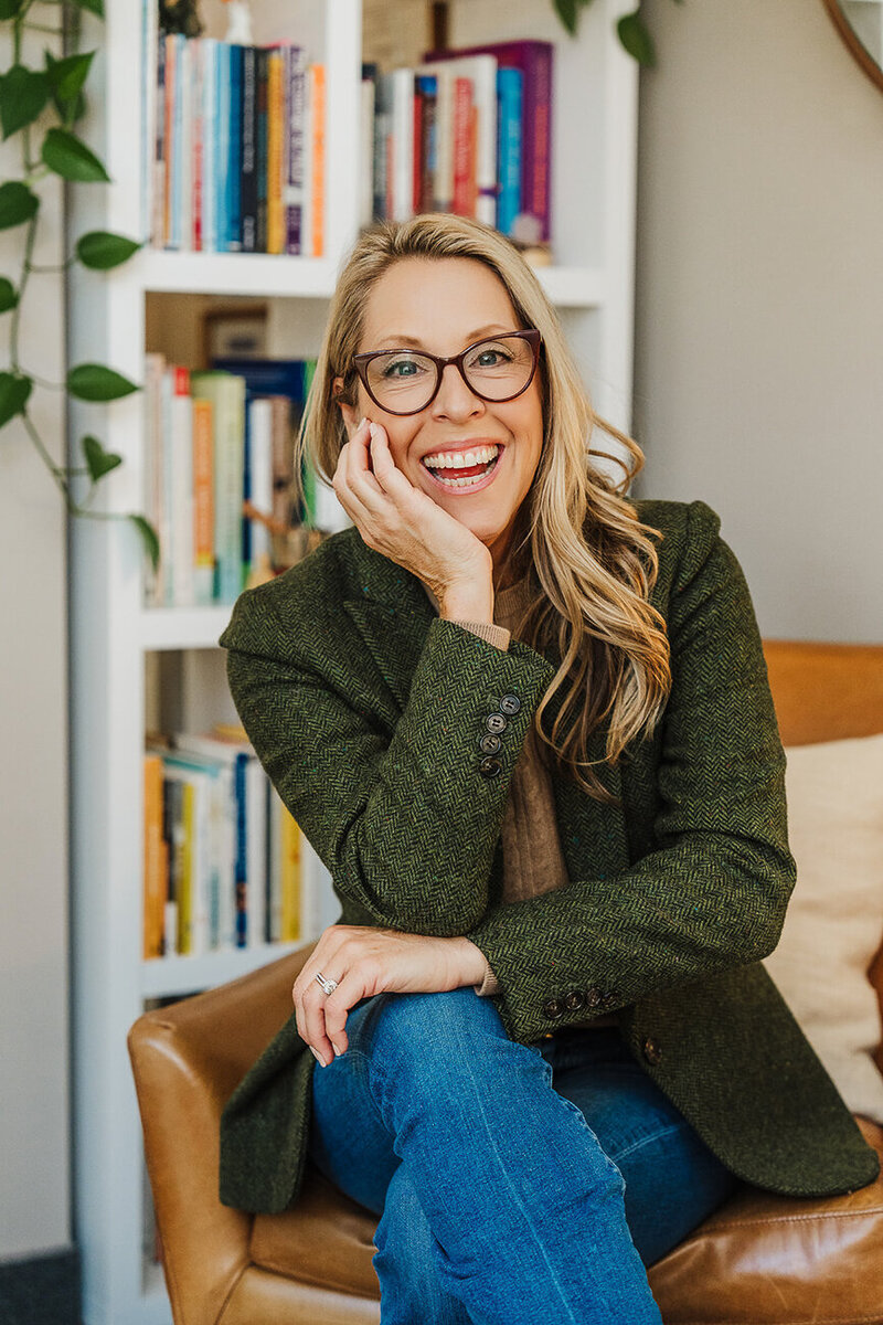 woman laughs while sitting in leather chair for boston headshot