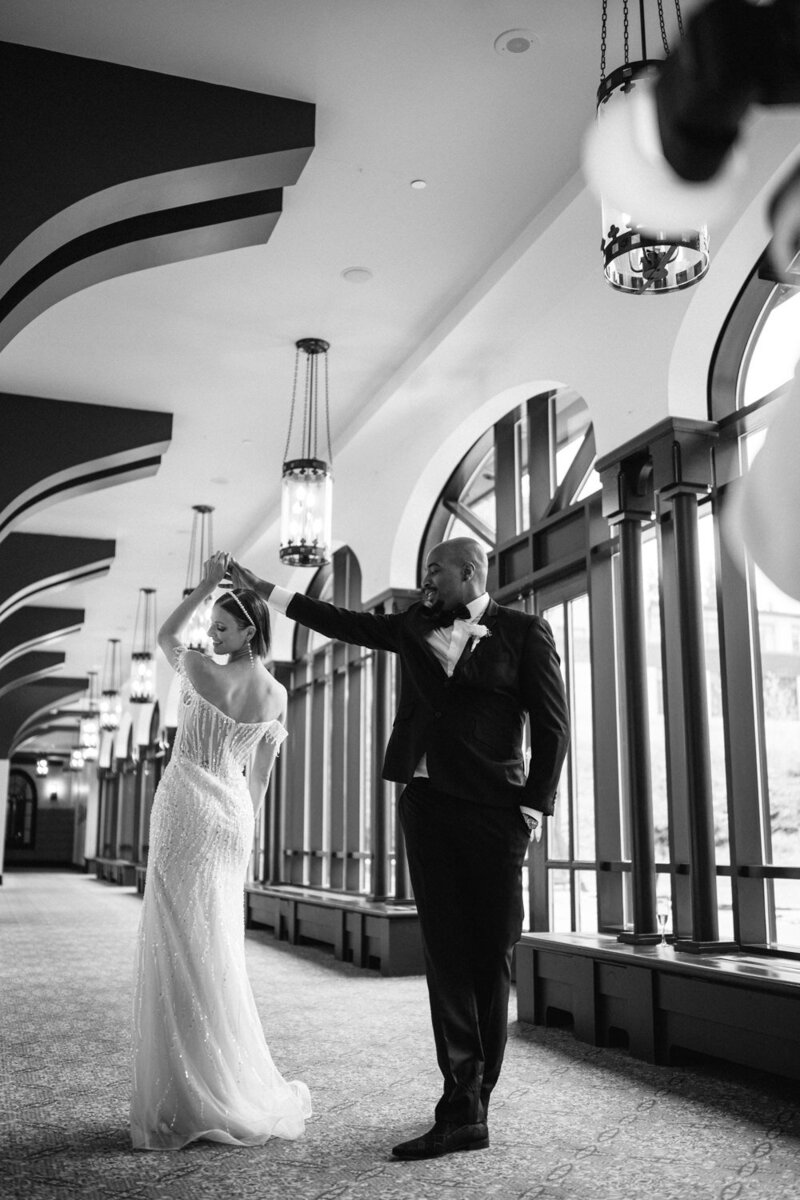 Le marié fait tournoyer sa femme élégamment vêtue lors de leur danse dans un hôtel prestigieux à Montréal, instant romantique et raffiné capturé dans un décor luxueux