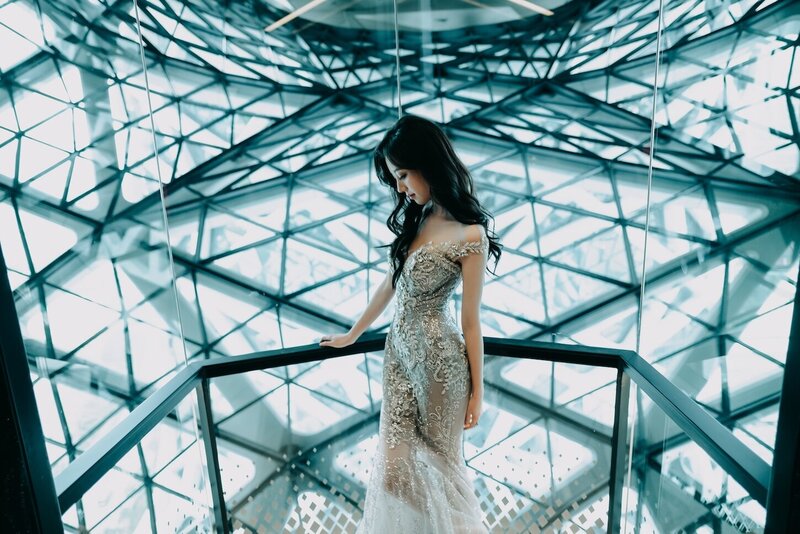 A woman in an abstract geometric lit room wearing a stunning couture dress.