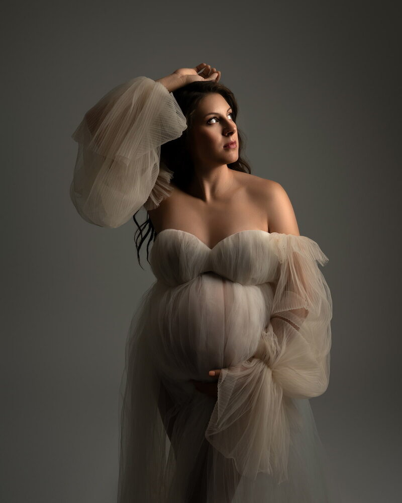 soft ivory tulle maternity dress with dramatic sleeves in moody lighting