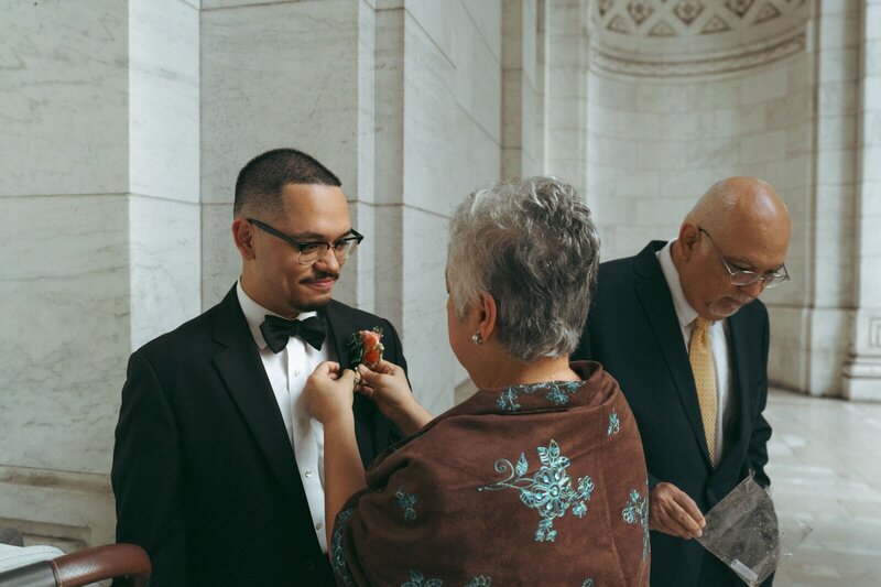 groom's mom fixing his flowers before NYPL elopement shot by Elsie Goodman Photography | NYC Elopement Packages