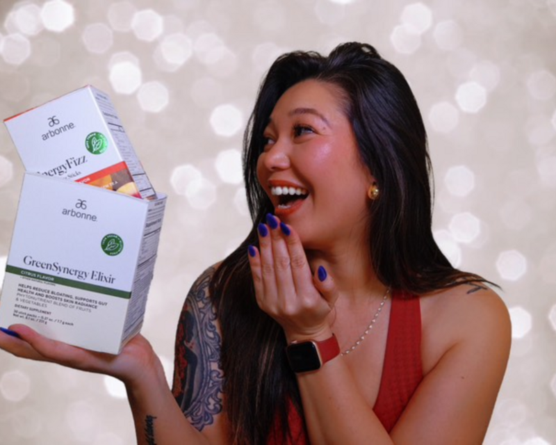 Jenni smiling while holding Arbonne wellness products, representing her authentic partnership and alignment with clean living and heart-led entrepreneurship