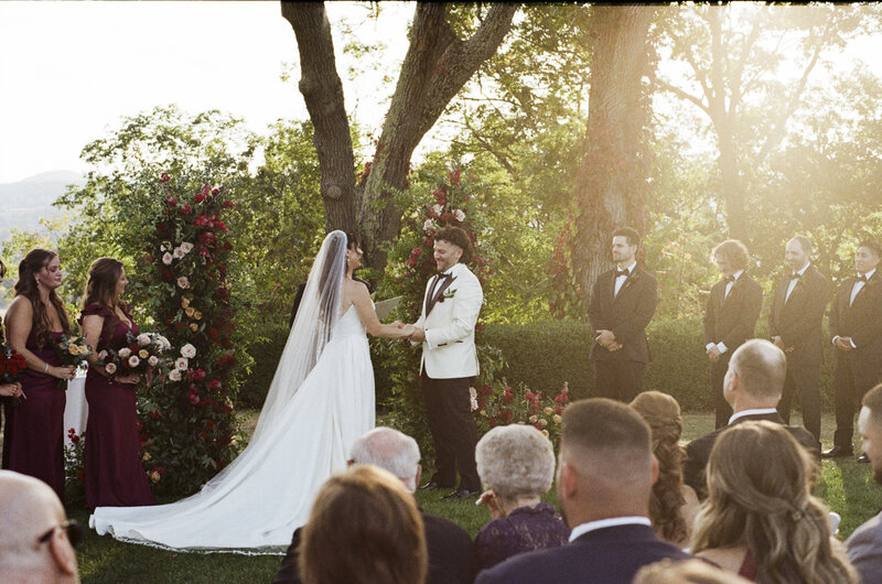 Golden hour sunset ceremony photo on 35mm film at Boscobel House & Gardens wedding with bride and groom holding hands