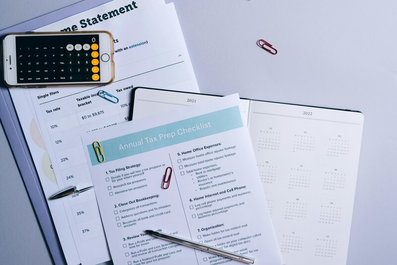 Close-up of an annual tax prep checklist, pen, and paperclips on top of financial documents, highlighting payroll preparation tasks