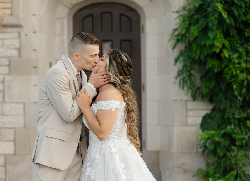 A newly married couple kissing in front of a old door at Venue3Two with a West Michigan wedding photographer