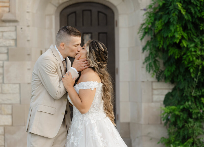 A newly married couple kissing in front of a old door