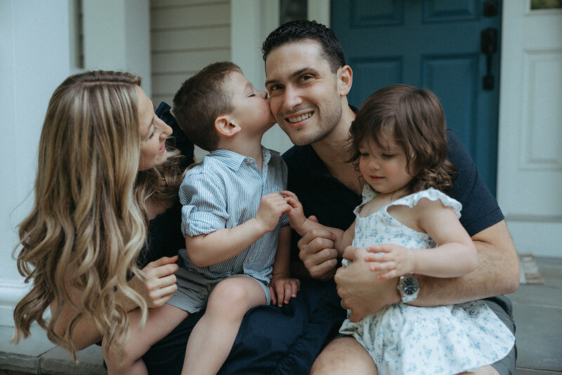 couple holding kids on front steps during at home family photos captured by NYC family photographer Elsie Goodman 